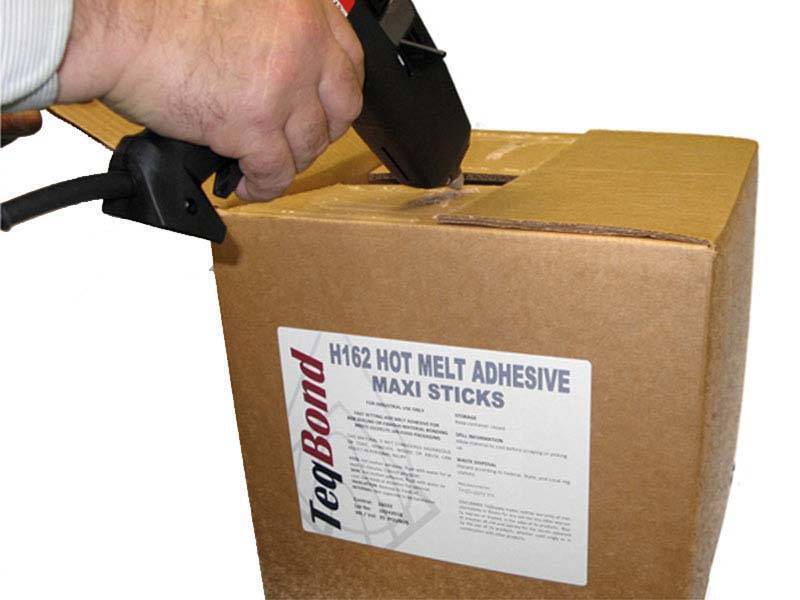 hand holding a hot glue gun to a cardboard box